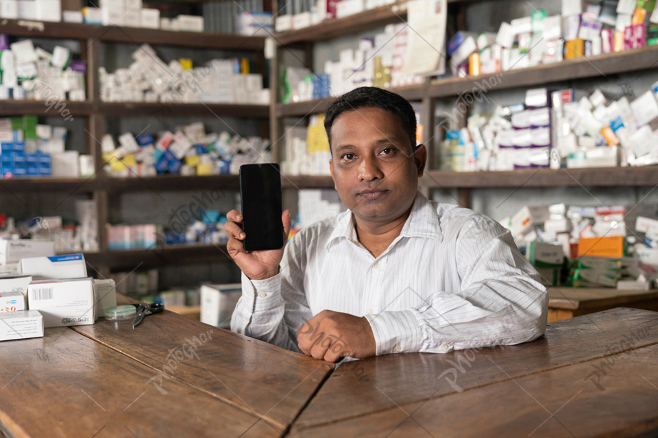 Bangladeshi Village pharmacist using mobile to