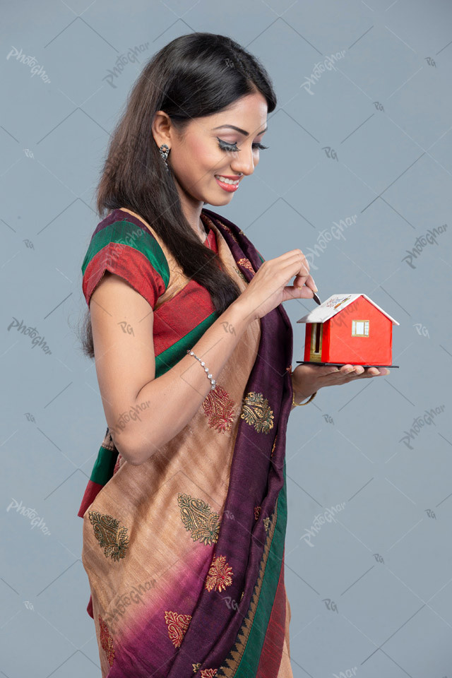 Bangladeshi housewife saving coin into piggy bank