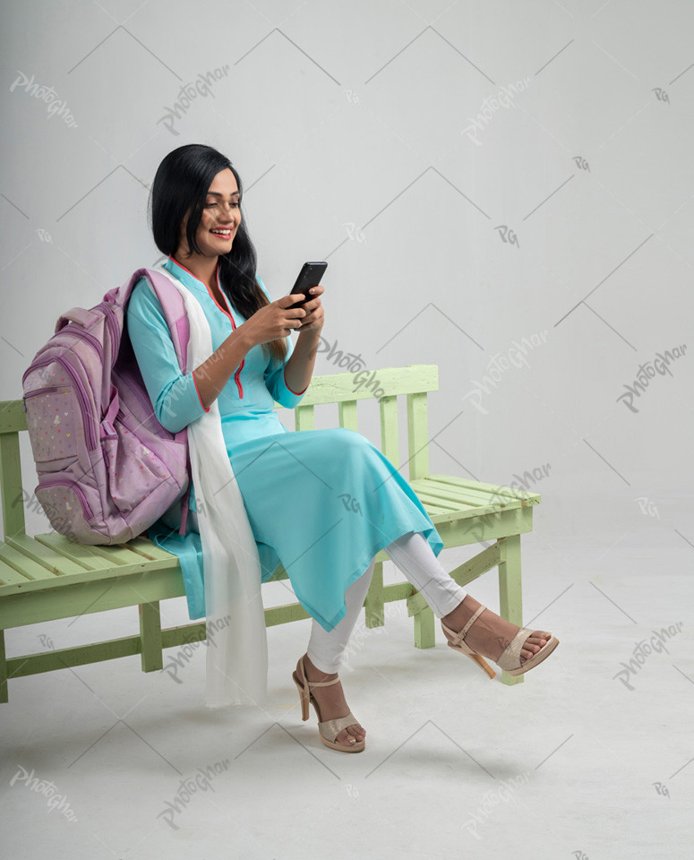 Beautiful university student on bench using mobile phone