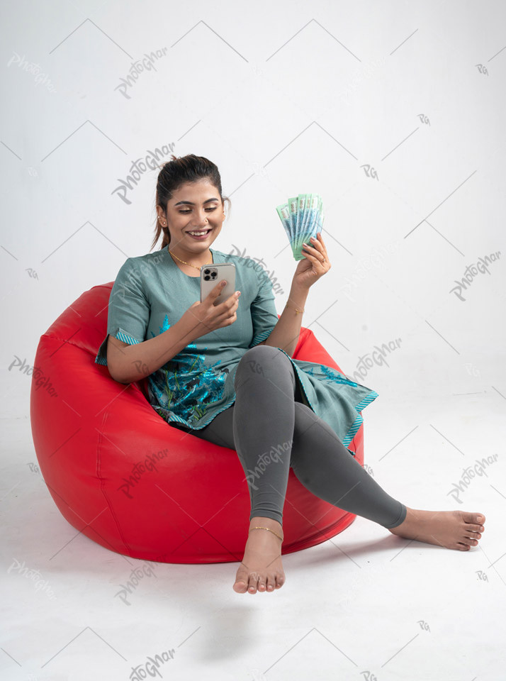 Cheerful woman showing money and typing phone