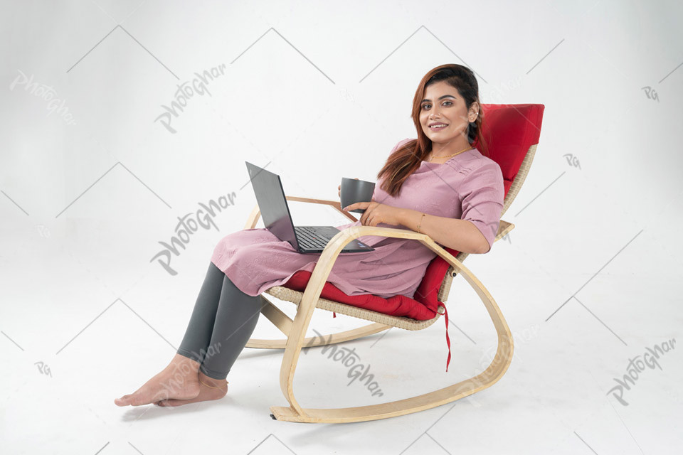 Confident young lady having coffee with laptop