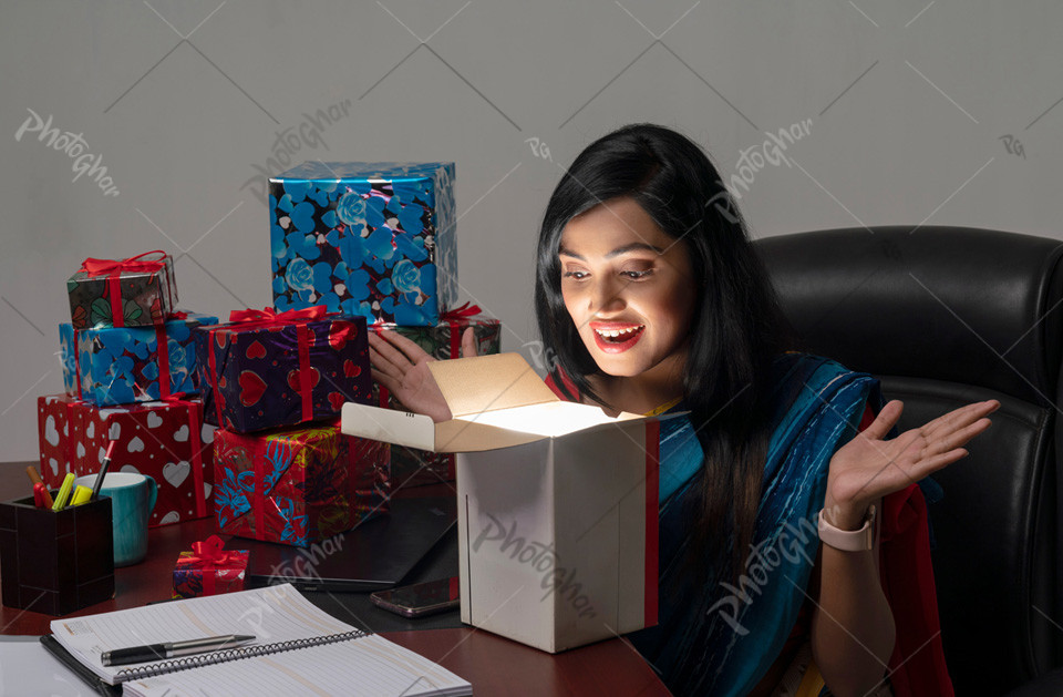 Excited Female office worker taking surprise gift