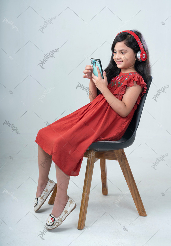 Female kid wearing headphone using mobile