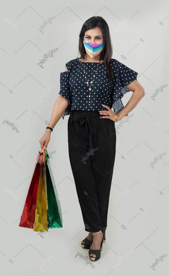 Full body asian woman in mask holding shopping bags