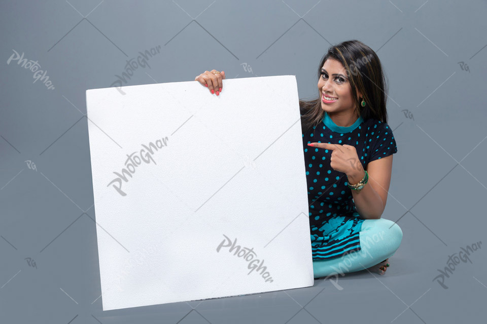 Gorgeous young woman pointing and holding placard