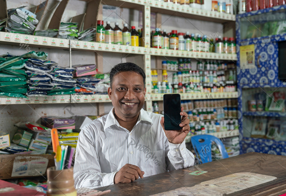 Happy Shopkeeper fertilizers shop holding a mobile phone