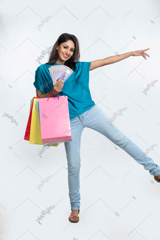 Happy woman shopper holding money and paper bags