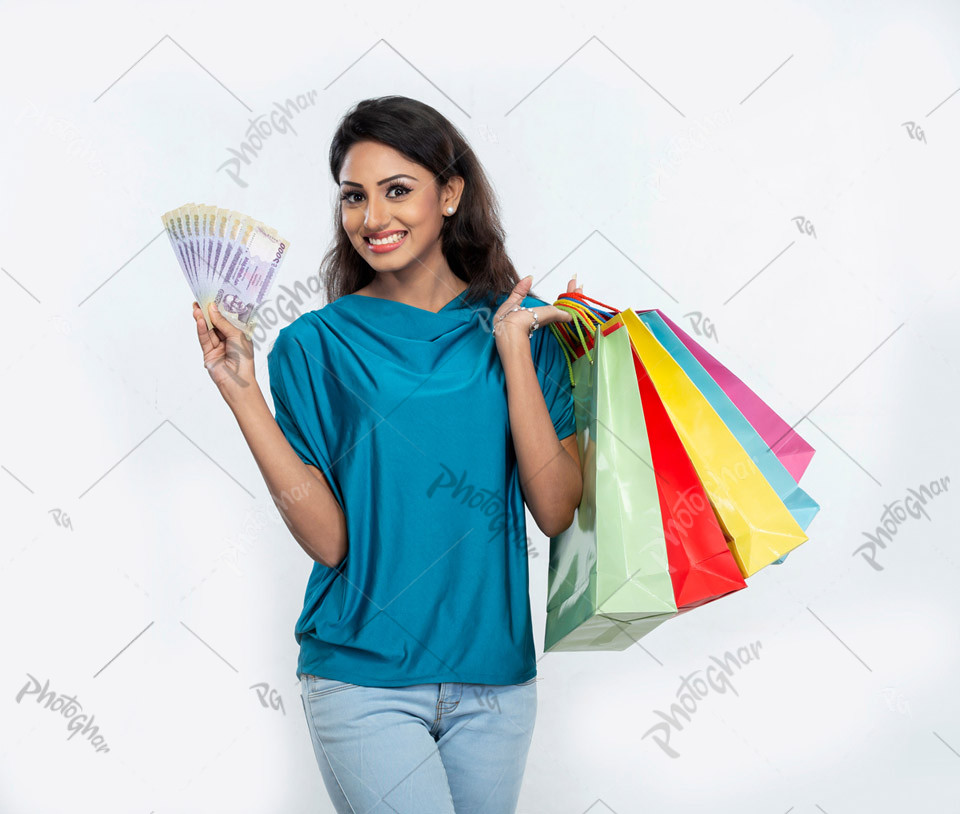 Joyful woman showing money and shopping bags