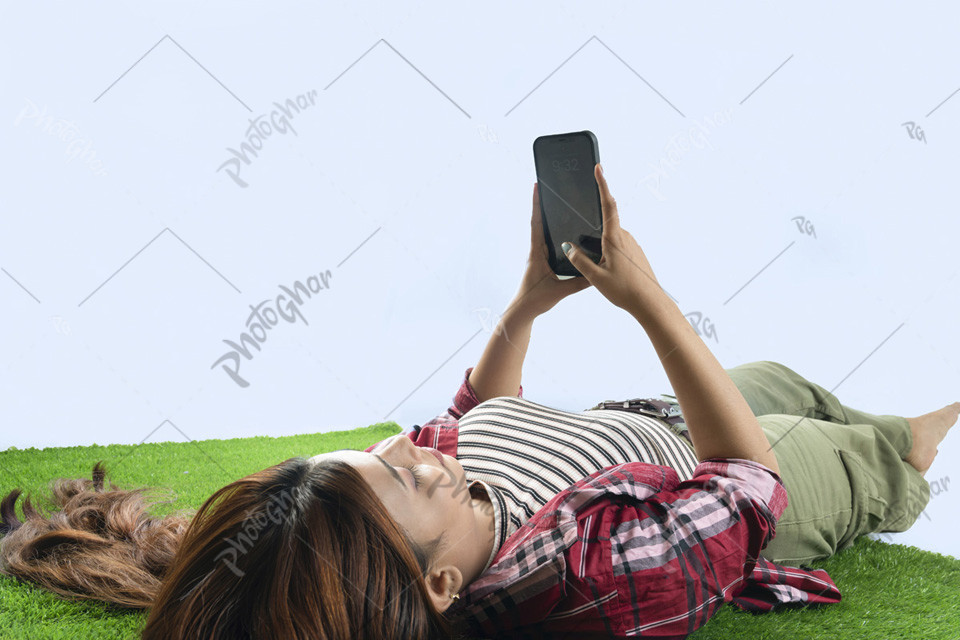 Lying woman searching smartphone on grass