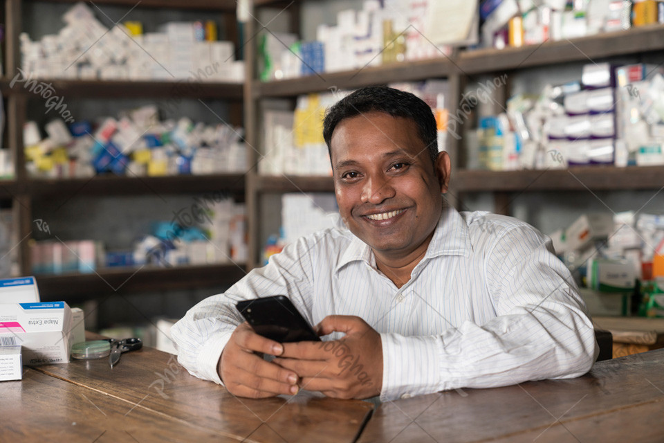 Male pharmacist sitting store dispensary