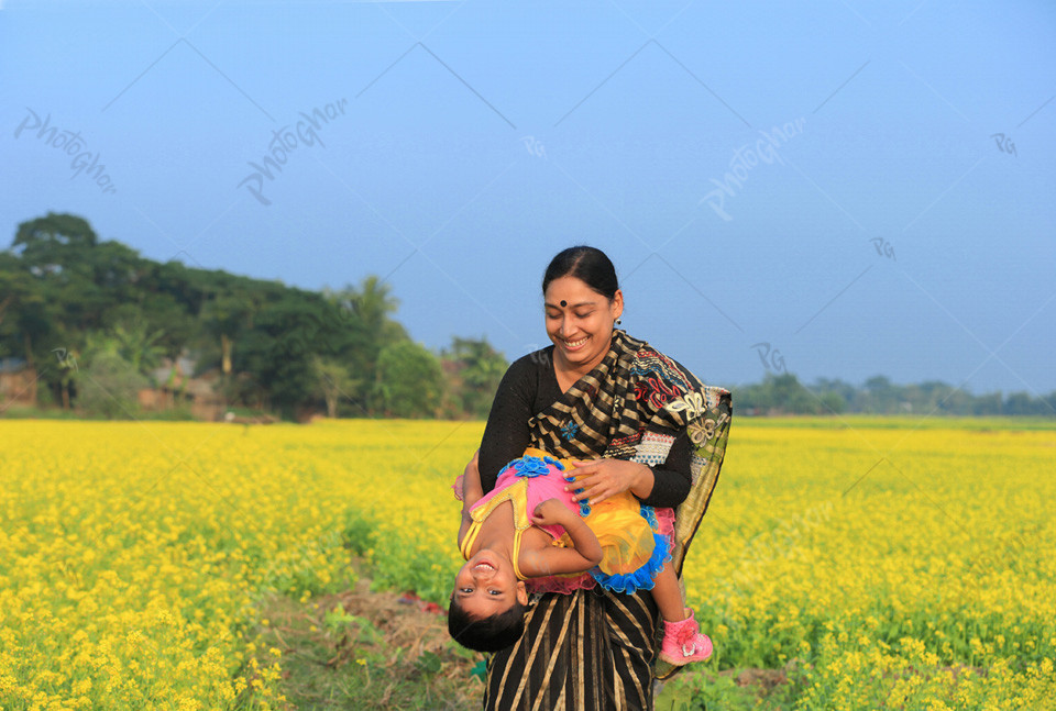 Mother and baby playing in the mustard flowers