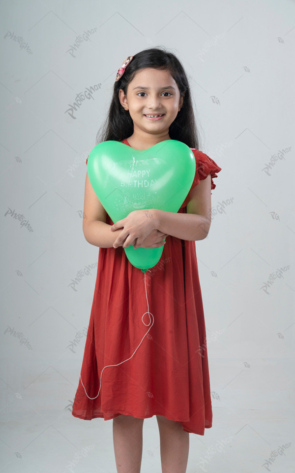 Portrait of a cute smiling little girl holding a green heart