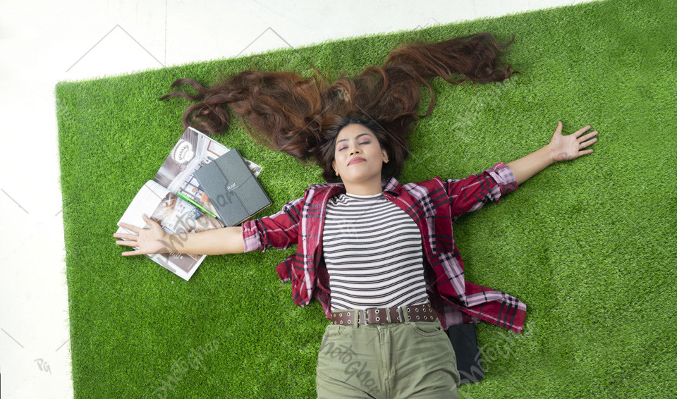 Relaxing woman lies on green field