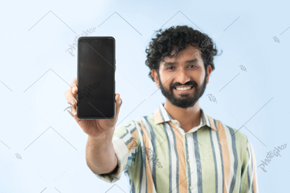 Smiling young man showing smartphone