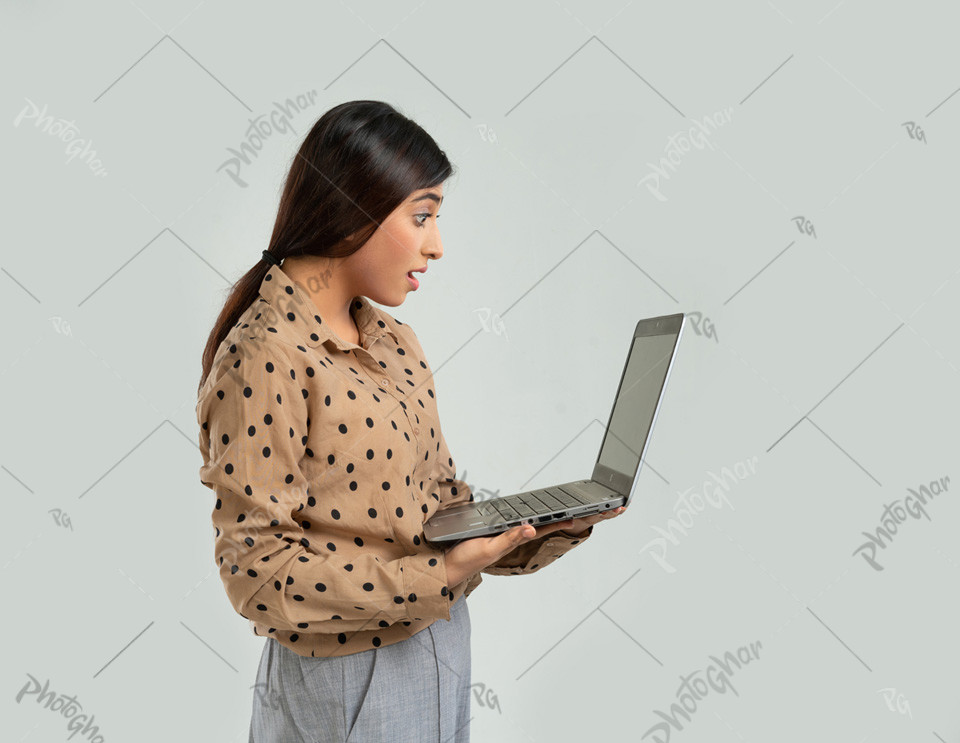 Surprised young woman holding laptop