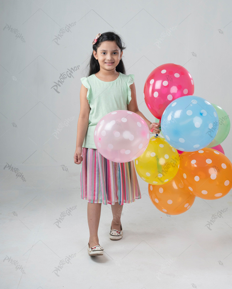 Sweet smiling little girl holding colorful heart shaped balloon