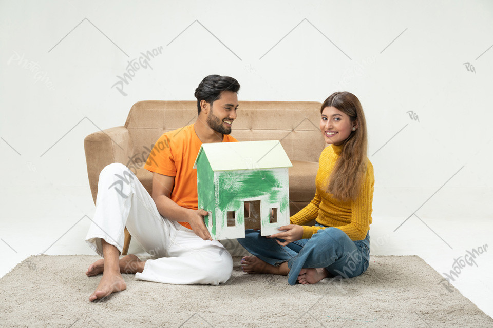 Young couple holding home structure