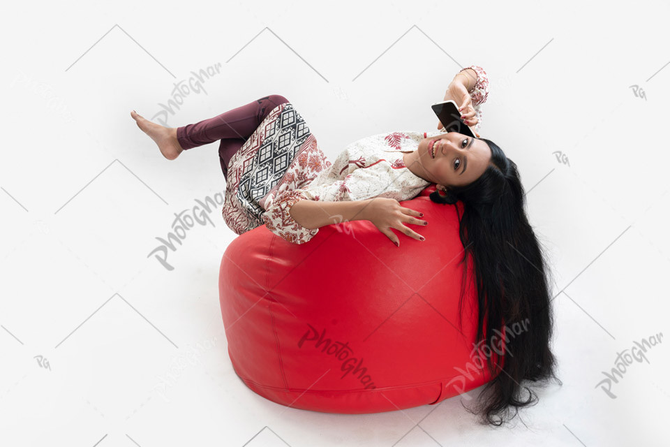 Young girl talking on phone, laying on bean bag