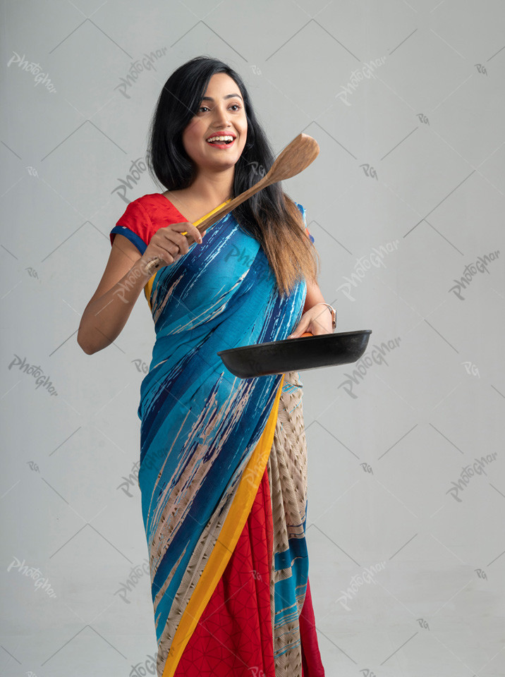 Young housewife standing with frying pen