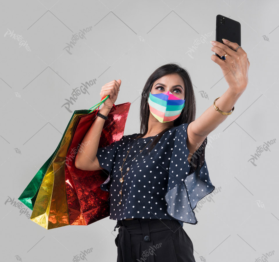 Young lady shopper in mask on her face, taking selfie