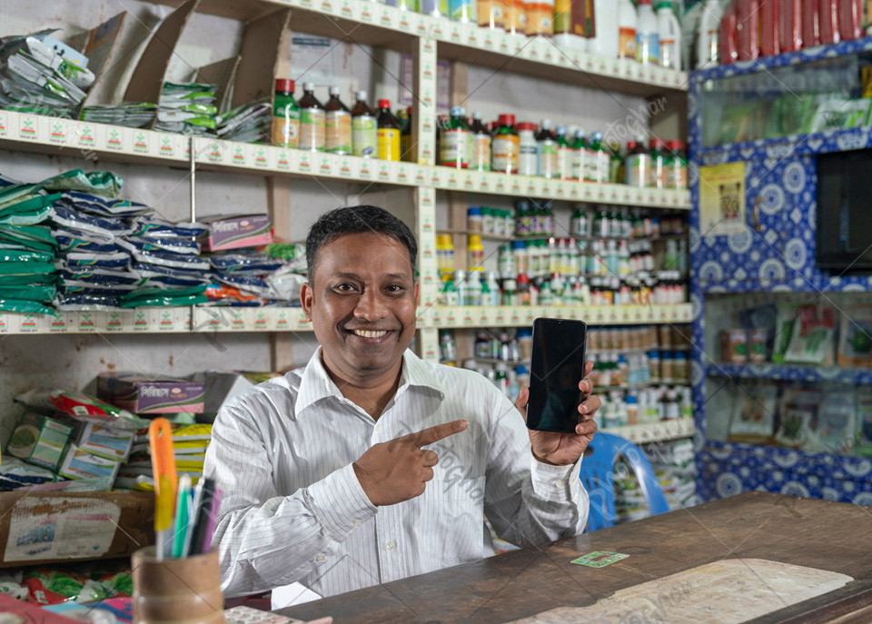 shopkeeper of fertilizers pointing mobile apps